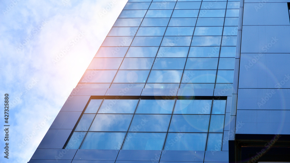 Glass clad facade of a modern building covered in reflective plate glass. Glass clad facade of a modern building covered in reflective plate glass.