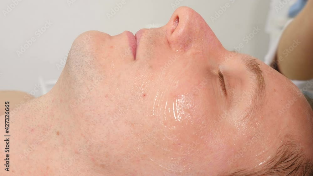 Cosmetology, cosmetic procedures for men. close-up. man lying on couch and getting facial skin care procedure, at beauty clinic. Skin care, dermatology treatment. Beautician applies gel before therapy Cosmetology, cosmetic procedures for men. close-up. man lying on couch and getting facial skin care procedure, at beauty clinic. Skin care, dermatology treatment. Beautician applies gel before therapy
