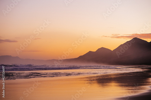 Sunset a a beautiful beach on an empty shore on fuerteventura, spain with crushing waves