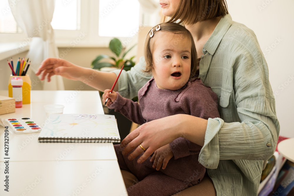 Girl with down syndrome drawing at home with her mother Girl with down syndrome drawing at home with her mother