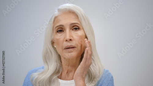 Fotografie Relaxed woman taking care about face indoors