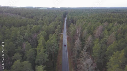 Car driving through a forest street in bavaria, topdown follower drone photo