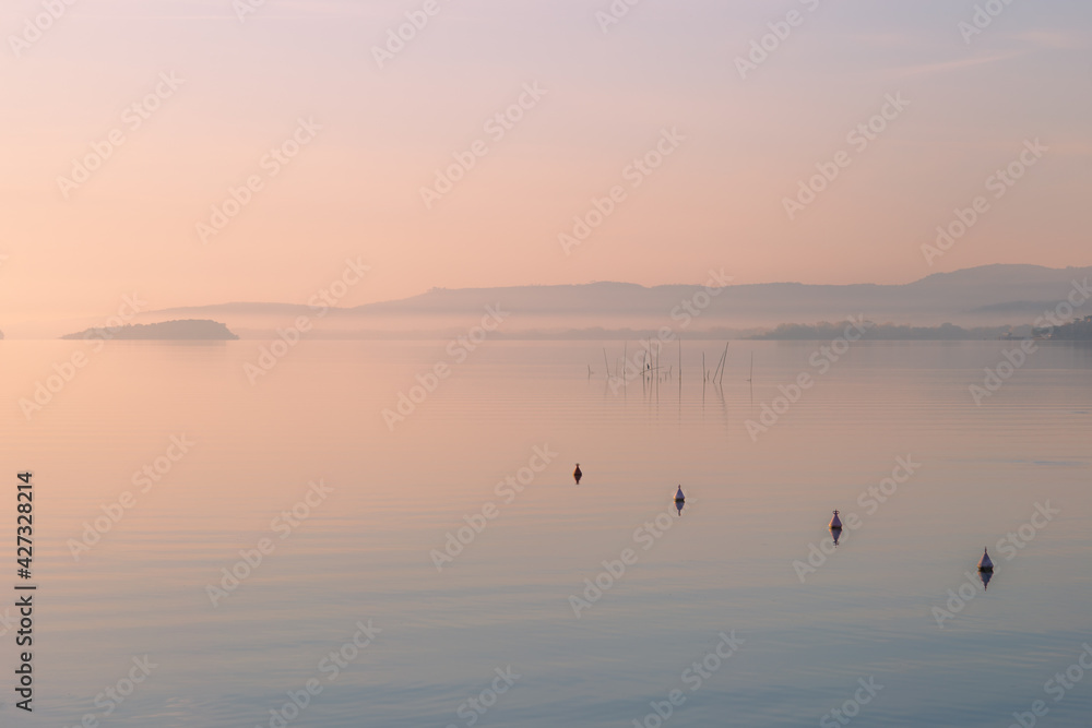 Peaceful and dreamlike view of a lake, with a line of buoys in the foreground