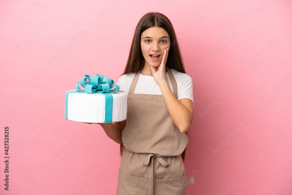 Little girl with a big cake over isolated pink background with surprise and shocked facial expression Little girl with a big cake over isolated pink background with surprise and shocked facial expression