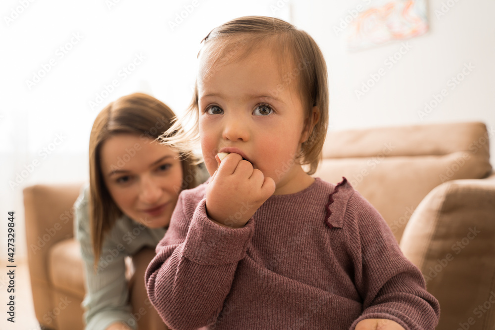 Baby with down syndrome eating apple with her short haired mother Baby with down syndrome eating apple with her short haired mother