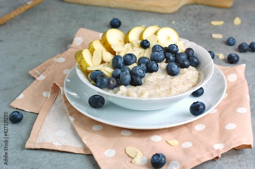 Creamy buckwheat porridge with pear, blueberry and almond in white bowl