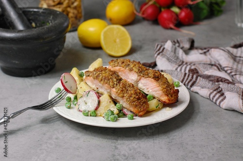 Fresh potato salad with peas, radish and roasted salmon with walnut crust