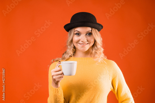 Espresso or Americano, a young stylish blonde in a bowler hat, holding a cup in her hands.