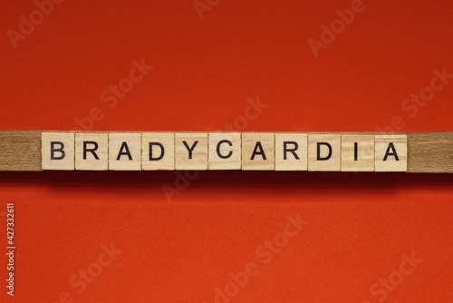 text the word bradycardia from gray wooden small letters with black font on an red table photo