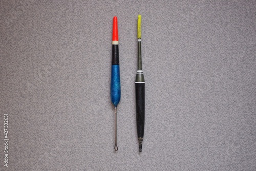 two long colored plastic fishing floats lie on a gray table