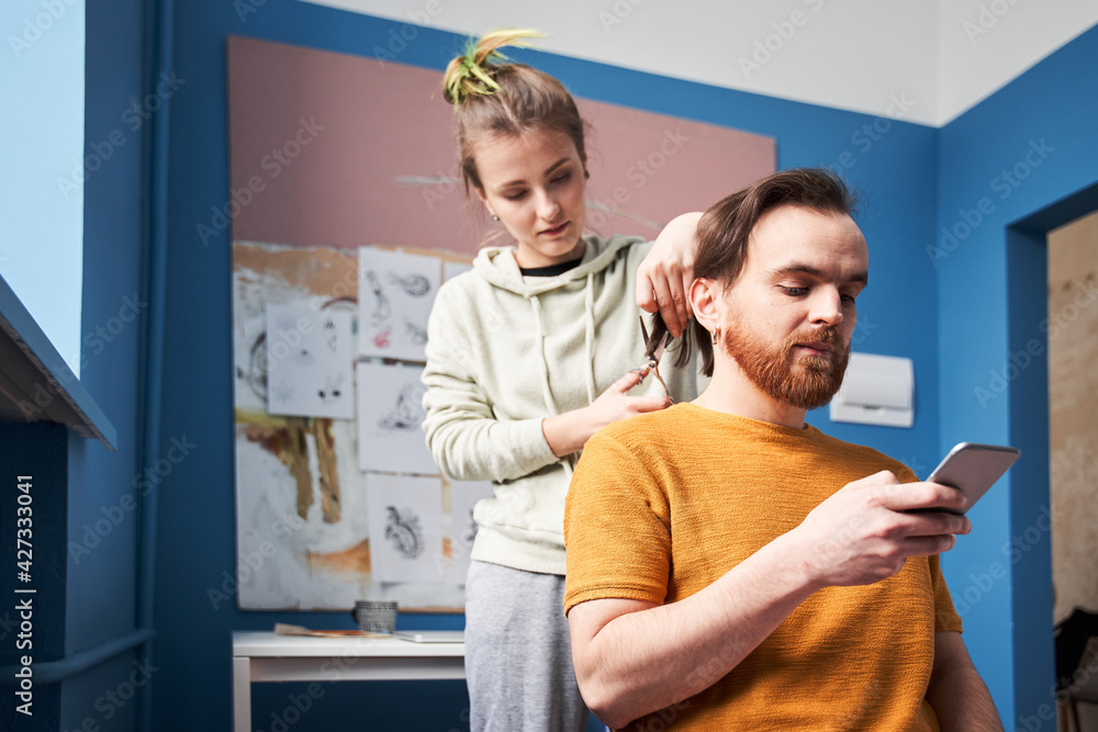 Obraz premium Woman with color hair cutting hair of her bearded man