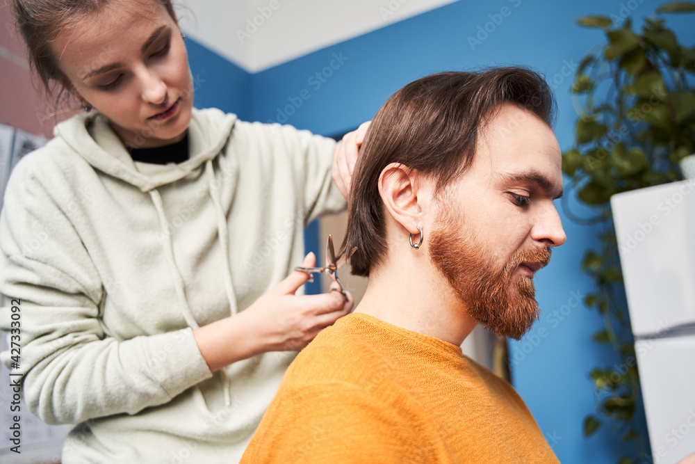 Obraz premium Couple cutting their own hair at home with a comb and scissors