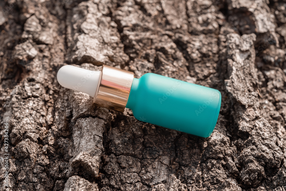 Cosmetic serum bottle mockup on tree bark background. Anti aging product, luxury body care and organic science concept. Moisturizing beauty skincare cosmetics packaging. High angle view Cosmetic serum bottle mockup on tree bark background. Anti aging product, luxury body care and organic science concept. Moisturizing beauty skincare cosmetics packaging. High angle view