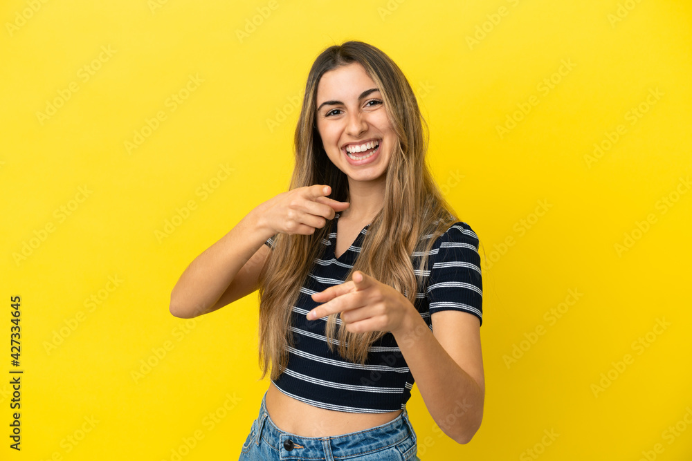 Young caucasian woman isolated on yellow background surprised and pointing front Young caucasian woman isolated on yellow background surprised and pointing front