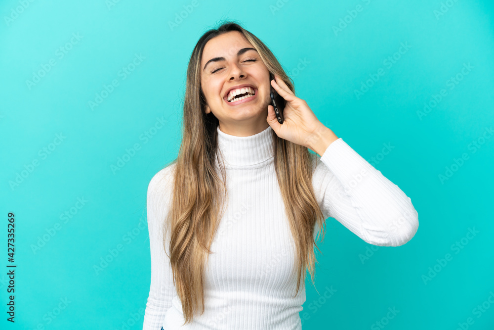 Young caucasian woman using mobile phone isolated on blue background laughing Young caucasian woman using mobile phone isolated on blue background laughing