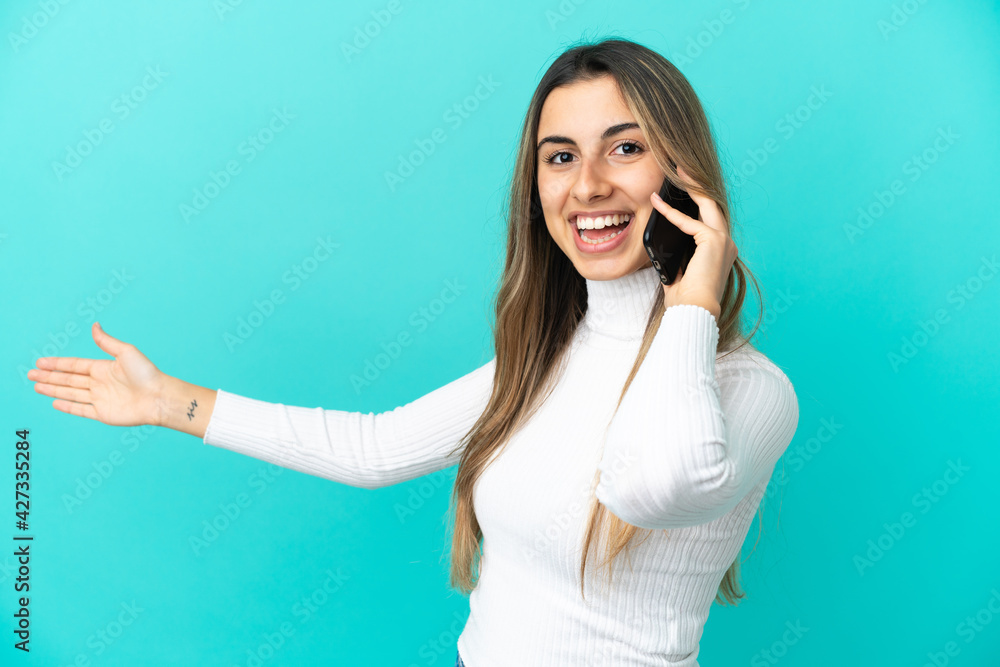 Young caucasian woman using mobile phone isolated on blue background extending hands to the side for inviting to come Young caucasian woman using mobile phone isolated on blue background extending hands to the side for inviting to come