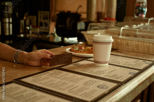 Close-up of a female customer presenting a credit card in a cafe