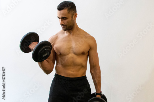 Jovem atleta, de torso nu, treinando funcional com haltere photo