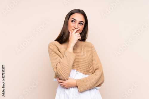 Young caucasian woman isolated on beige background having doubts and with confuse face expression