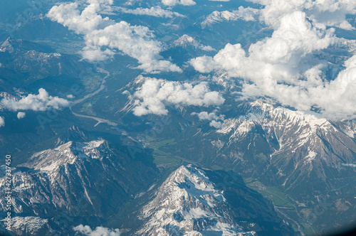 Snow-capped peaks of the Alps and a valley with a river seen from the plane. Concept: geography, air travel, alps seen from above