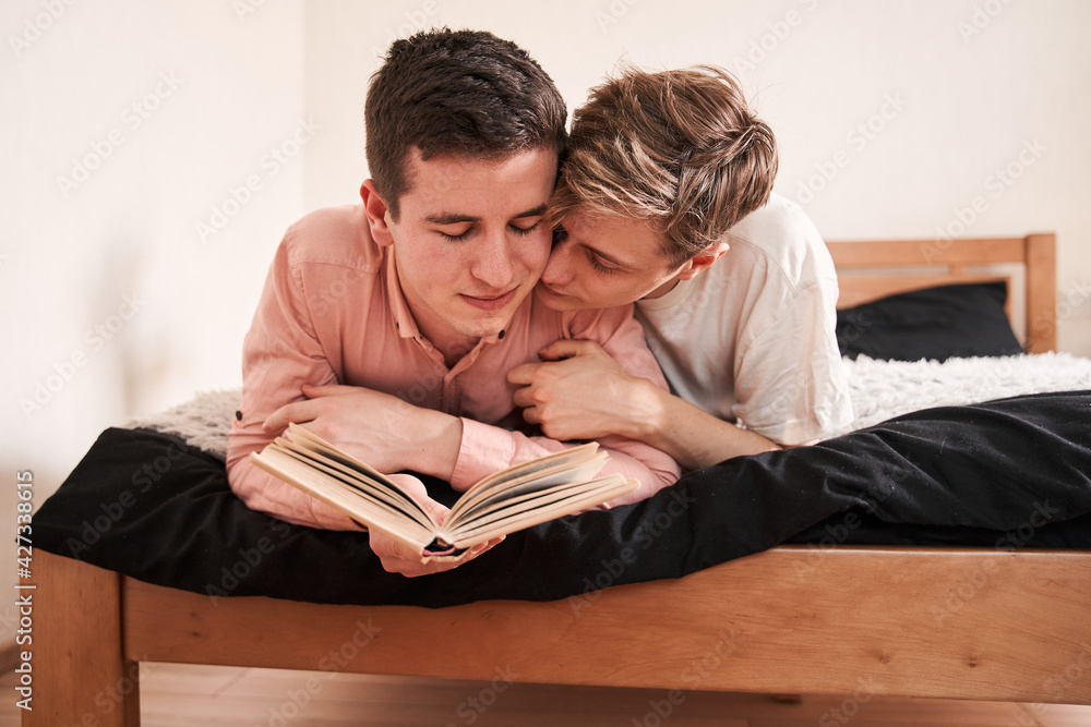 Two young gays excited of reading on the bed, while spending great time together
