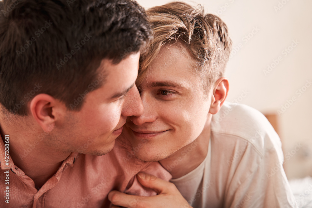 Homosexual couple laying close to each other, smiling and looking at each other Homosexual couple laying close to each other, smiling and looking at each other