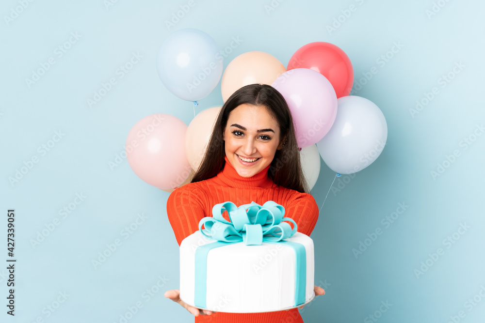 Young woman with many balloons isolated on blue background Young woman with many balloons isolated on blue background