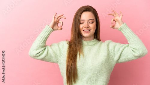Teenager girl over isolated pink background in zen pose