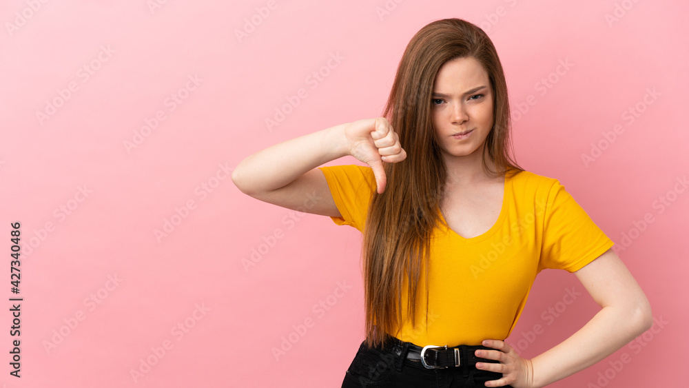 Teenager girl over isolated pink background showing thumb down with negative expression Teenager girl over isolated pink background showing thumb down with negative expression