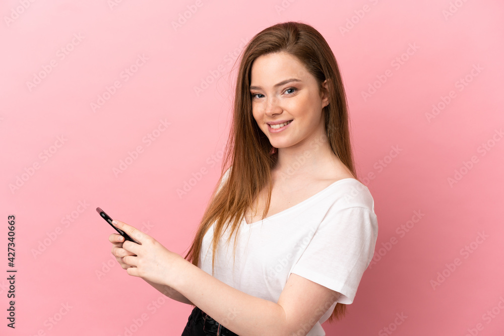 Teenager girl over isolated pink background sending a message or email with the mobile Teenager girl over isolated pink background sending a message or email with the mobile