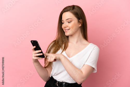 Teenager girl over isolated pink background sending a message or email with the mobile