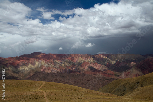 The famous Hornocal colorful mountains in Humahuaca  Jujuy  Argentina. The hiking path across the golden meadow and hills  into the mountain range. Beautiful stone colors and texture.