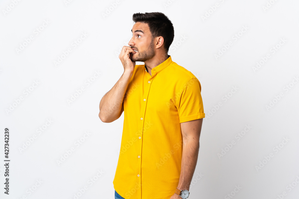 Young handsome man over isolated background is a little bit nervous Young handsome man over isolated background is a little bit nervous