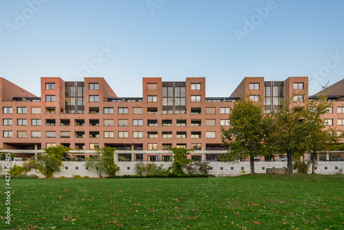 Outdoor scenery view on promenade riverside of Meuse river at Charles Eyck Park and modern residential building during sunset time in Maastricht, Netherlands.  