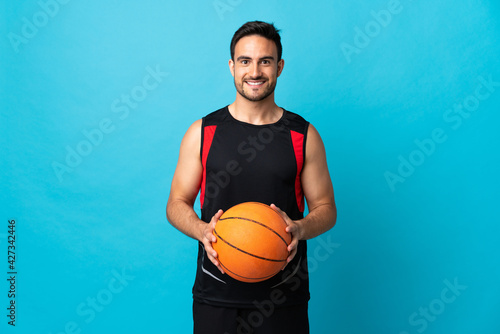 Young handsome man isolated on blue background playing basketball © luismolinero