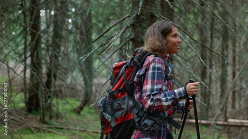 Woman with trekking poles hiking in forest. Female tourist walking in woods