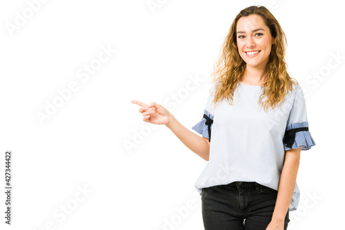 Attractive woman in her 20s pointing to copy space