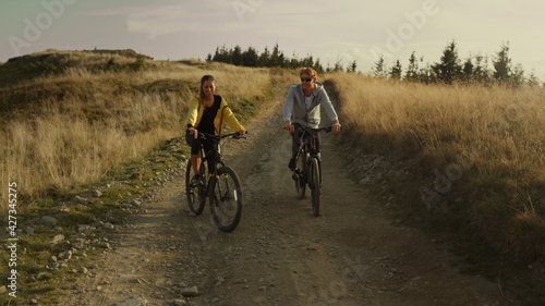 Couple riding sport bicycles on road. Happy cyclists exercising in mountains
