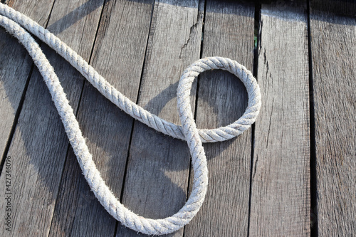 Ship ropes tied to knot isolated on wooden background closeup at the port.