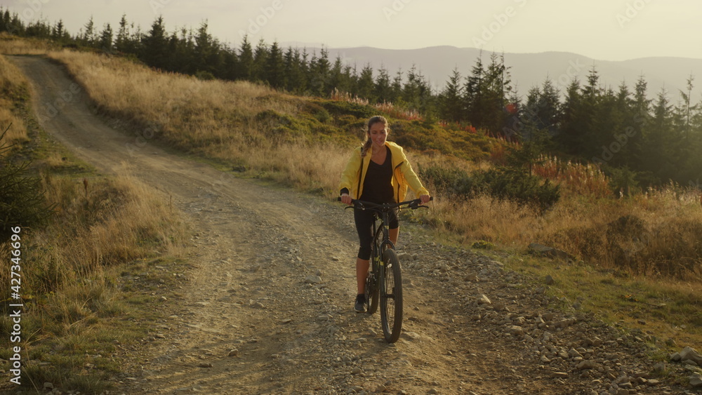 Focused woman riding sport bicycle on road. Cyclist exercising in mountains