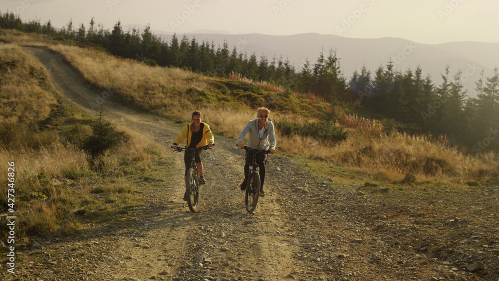 Couple on bicycles riding on mountain road. Happy bicyclists training outdoor