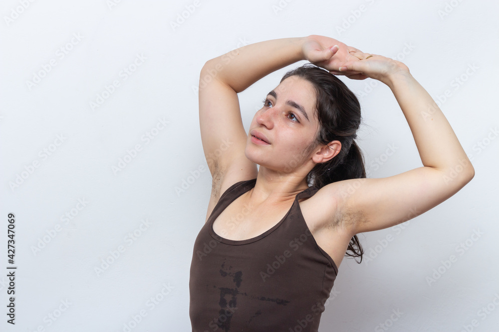 Brown tank top woman on white background with tied hair stretching Brown tank top woman on white background with tied hair stretching