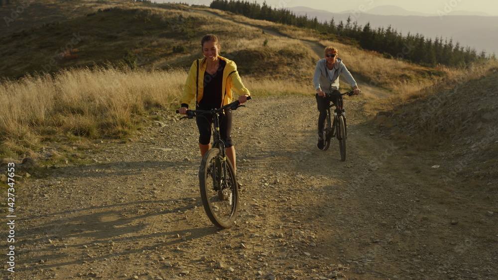 Naklejka premium Couple cycling on sport bikes in mountains. Man and woman riding mountain bikes