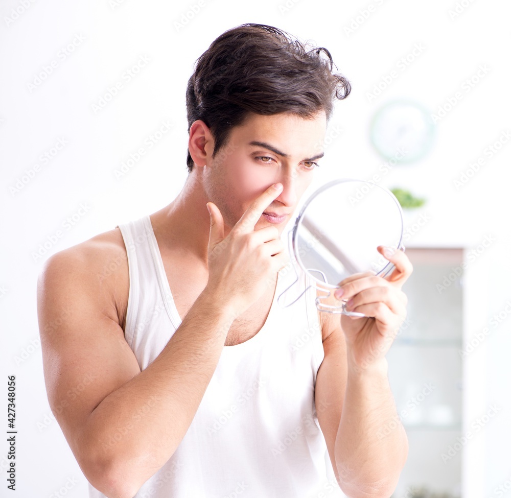 Young handsome man staring in the mirror