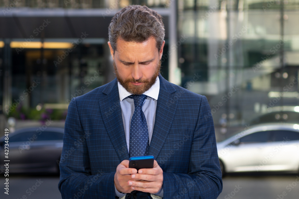 Business man texting message on smartphone near office. Business man texting message on smartphone near office.