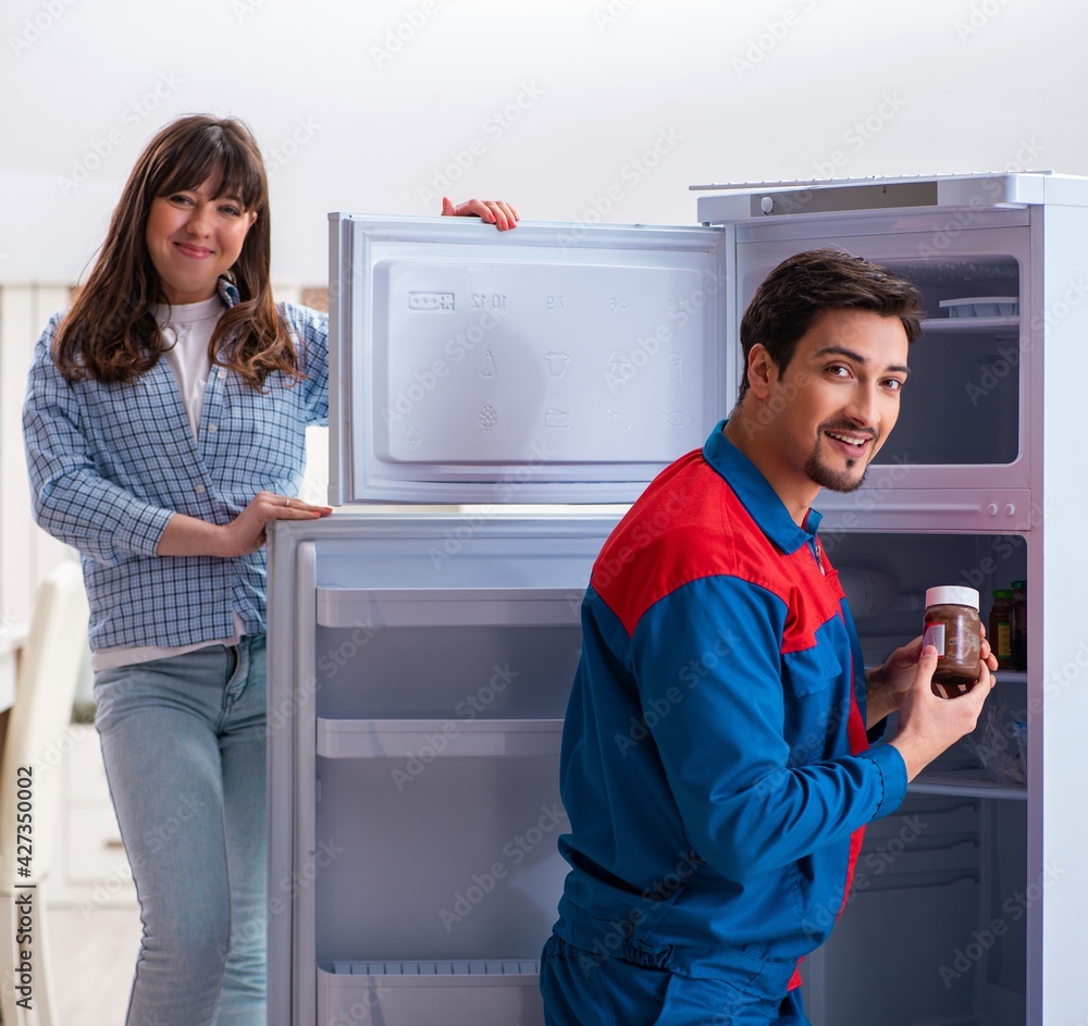 Man repairing fridge with customer Man repairing fridge with customer