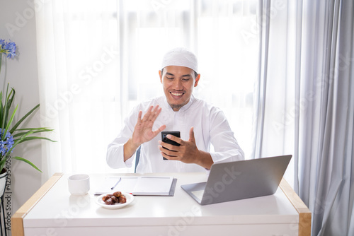 busy asian muslim businessman make a video call using his mobile phone