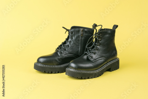 Leather brutal high-soled shoes with laces on a yellow background.