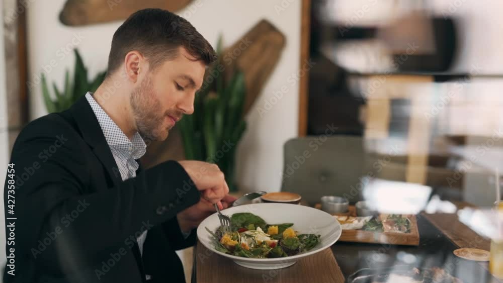 View through the window of a handsome man eating a salad