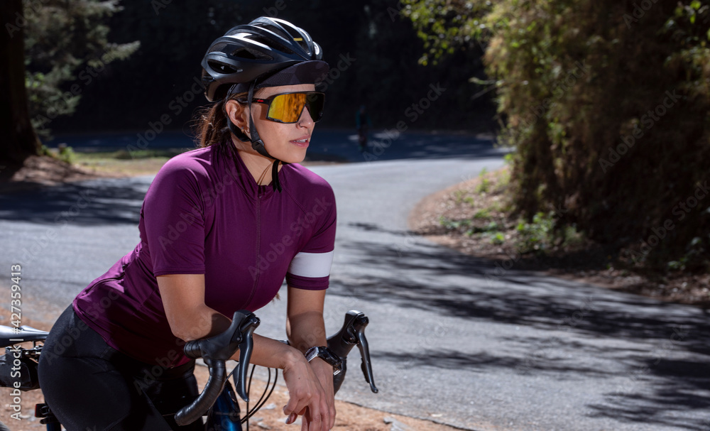 Mujer latina ciclista con su bicicleta de pista, usando casco y lentes de  sol, junto a la carretera en medio del bosque Stock-Foto | Adobe Stock